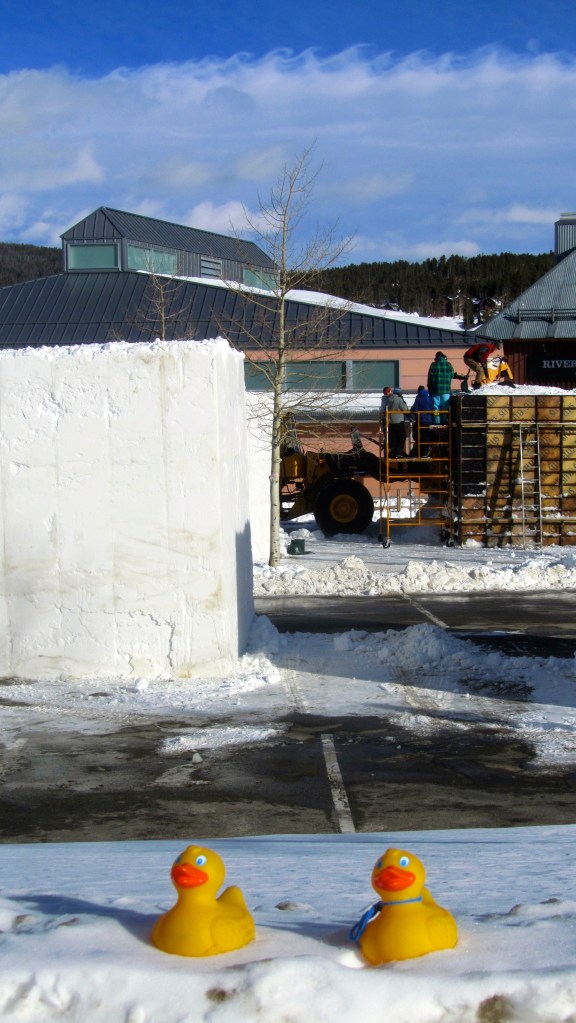 Humans stomping on snow in wooden frame to pack it hard