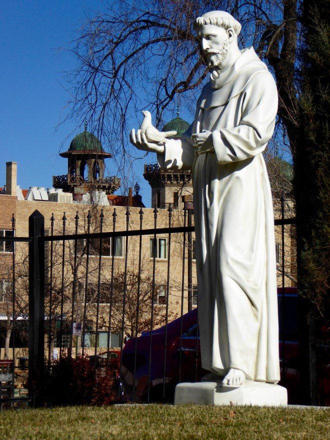 Statue in the garden. Through construction fence